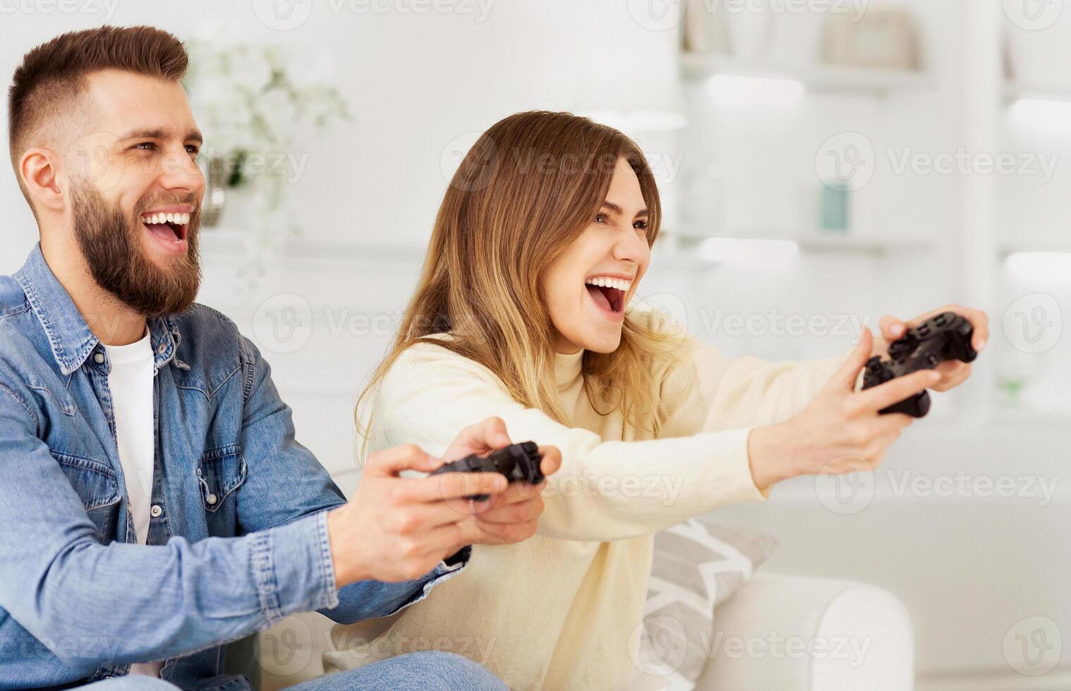 A man and a woman are focused on playing a game together, holding controllers and staring at the screen intently. photo