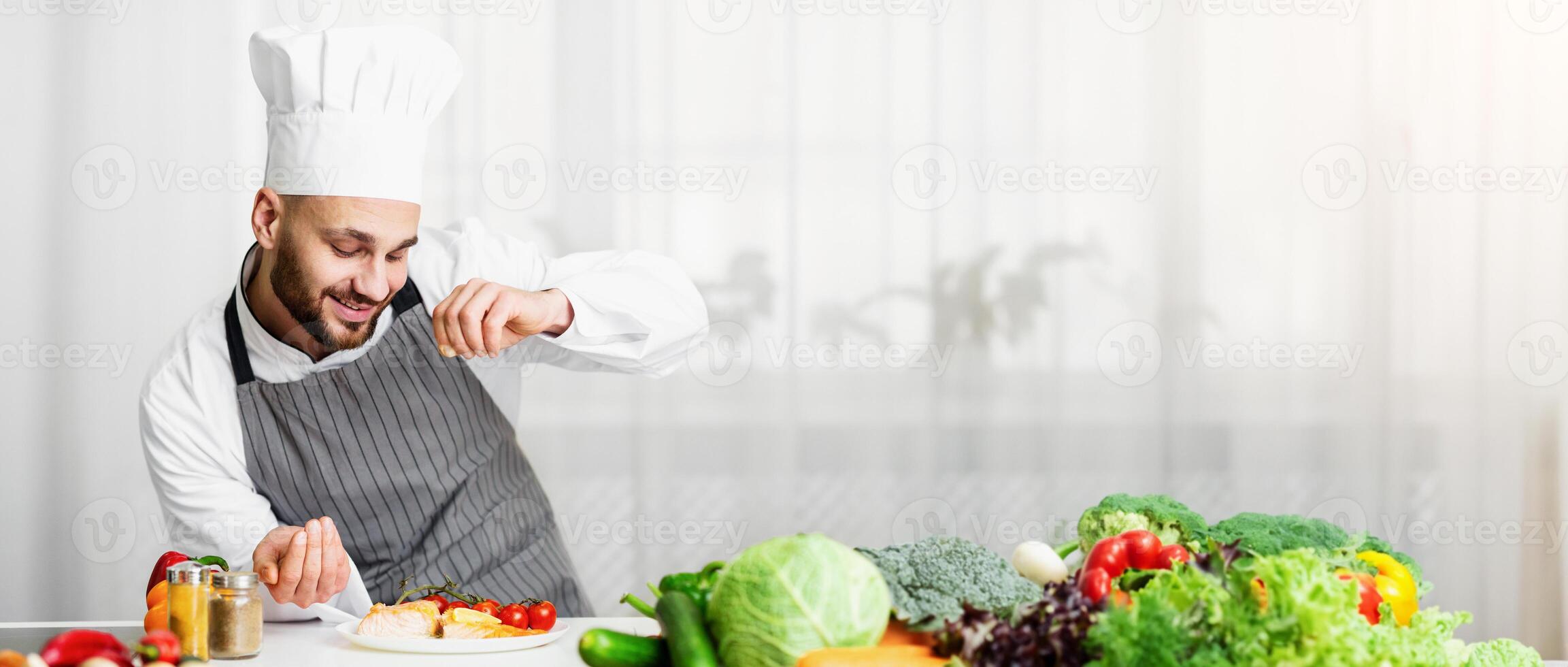 Cooking Fish. Male Chef Seasoning Roasted Salmon Steak Standing In Kitchen. Selective Focus photo