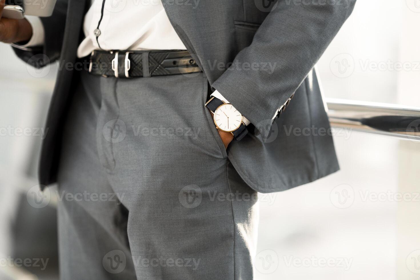 Fashion and Punctuality Concept. Man Hand with Wrist Watch in the Pocket of Stylish Pants photo