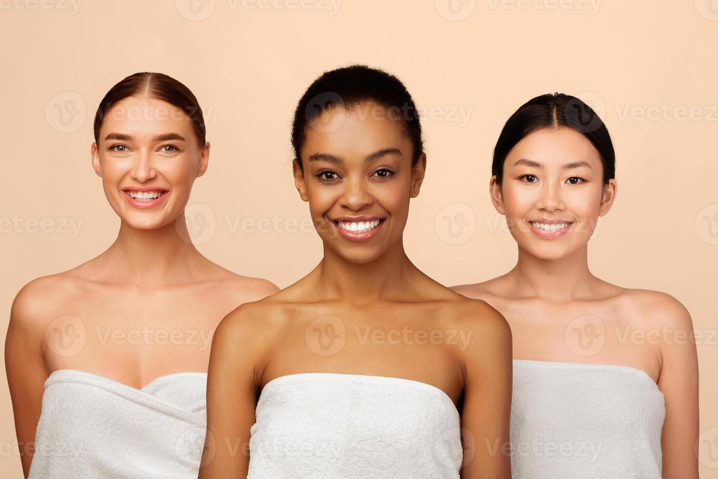 Three Attractive Women In Bath Towels Smiling At Camera Posing In Studio Over White Background. Body Care And Beauty photo
