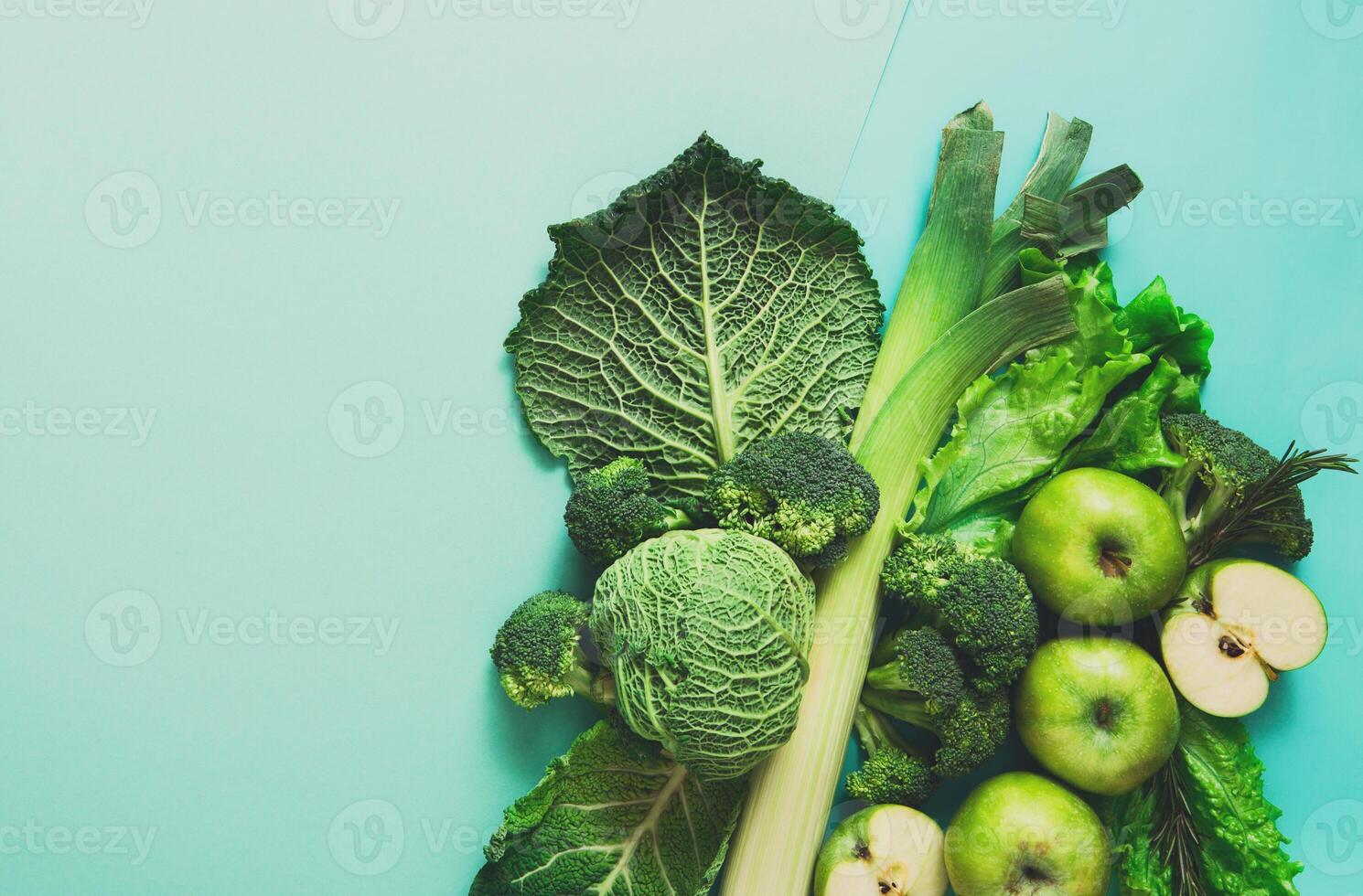 Green vegetables and fruits. Diet, detox and healthy food concept - top view flat lay of vegetarian meals on bright blue background. Ingredients for salad photo