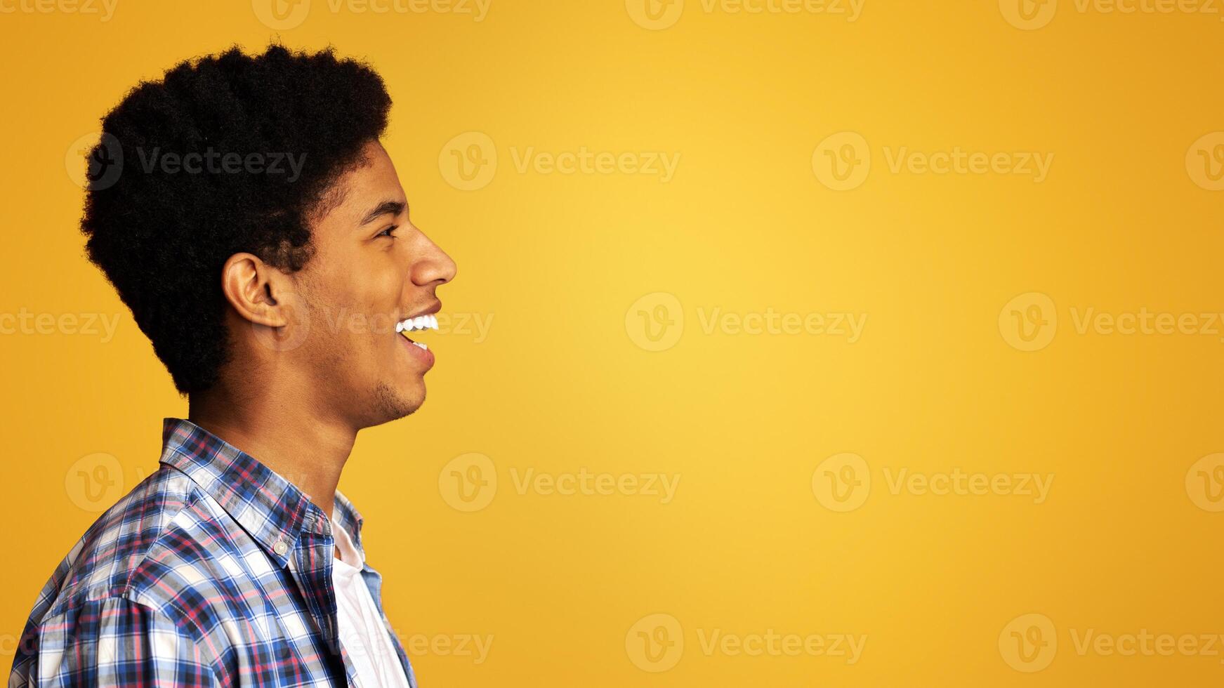 Profile portrait of smiling afro guy, looking at copy space over orange background photo