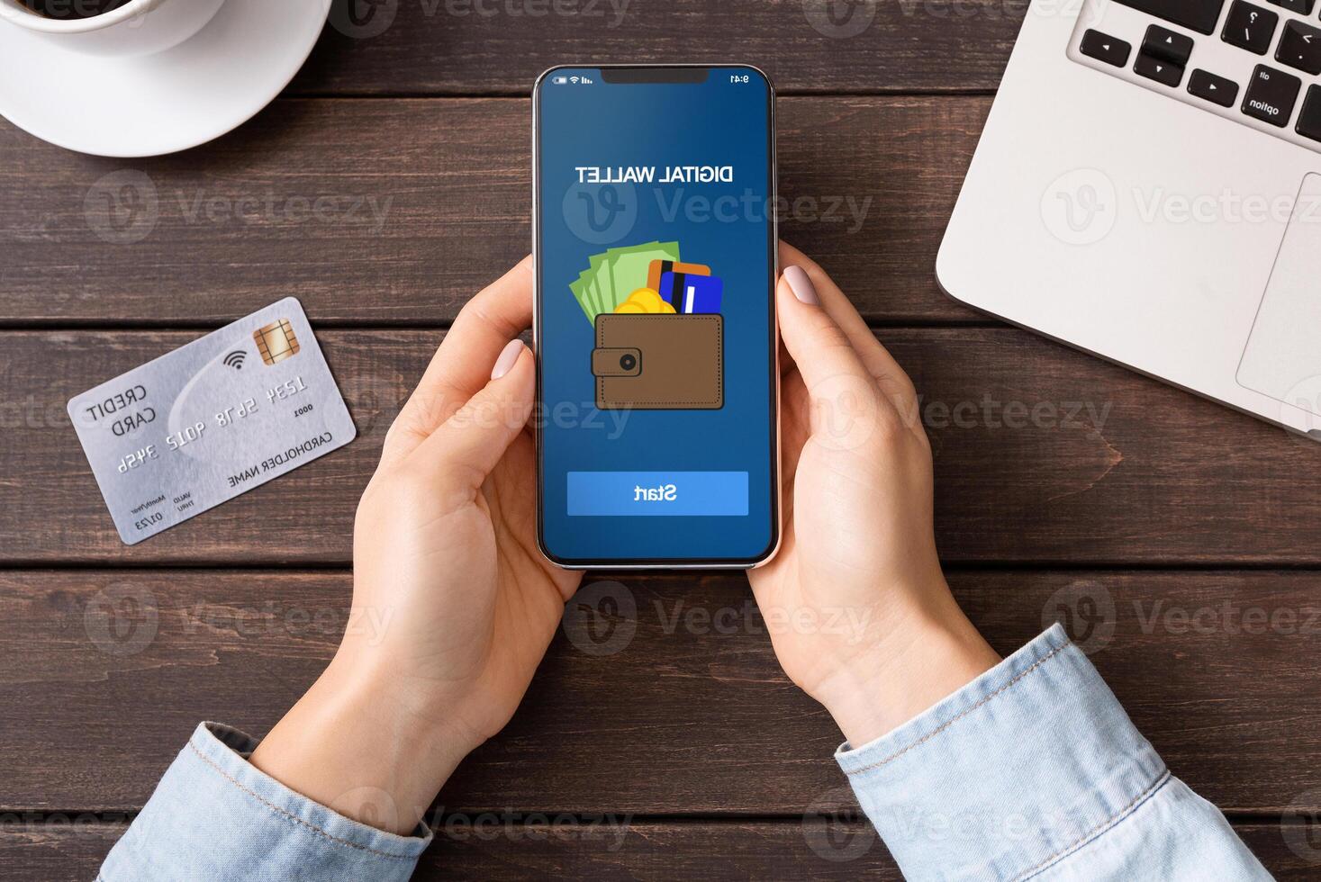 Mobile banking. Woman holding smartphone with digital wallet application. credit card on table, top view photo