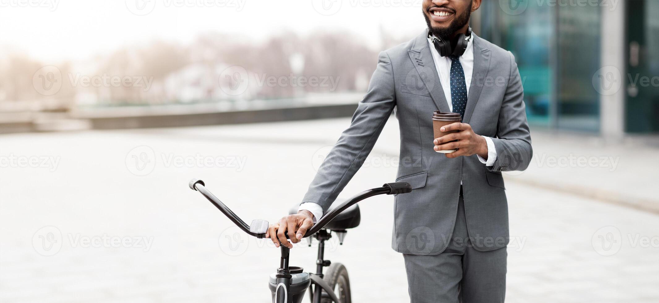 A businessman on a bicycle is in the city, drinking coffee. The scene is energetic and contemporary, highlighting a seamless blend of work and transportation in an urban setting, cropped photo