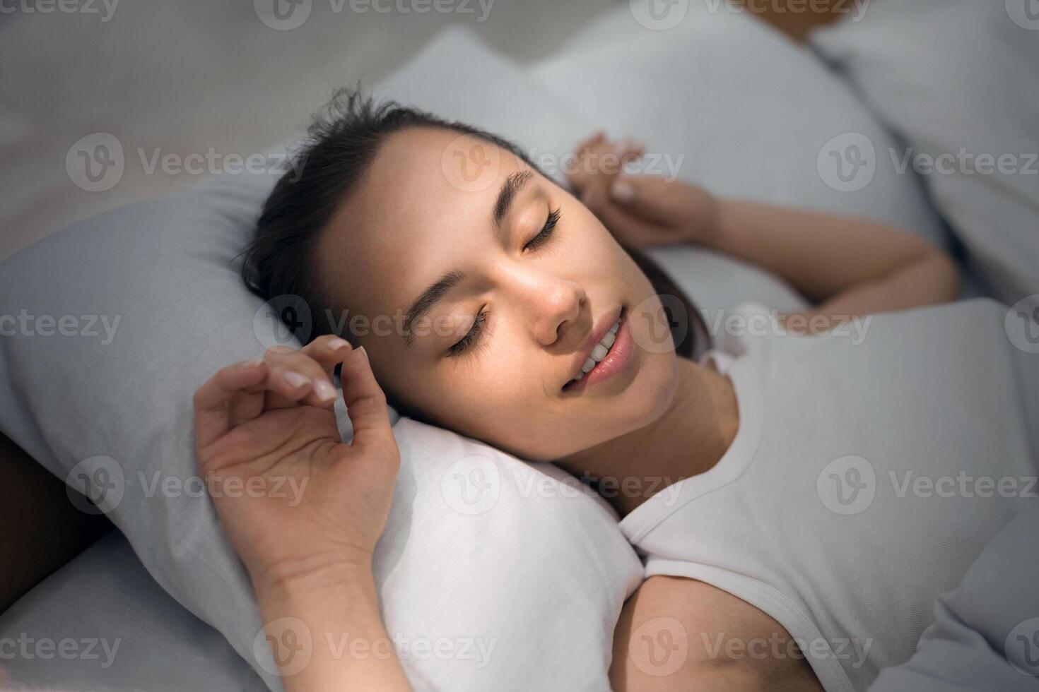 Young Woman Sleeping In Bed Comfortably And Blissfully With Sunbeam Dawn On Her Face photo