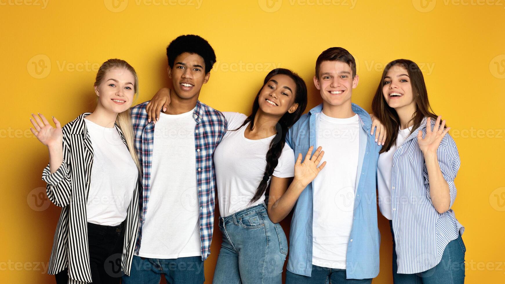 A group of multiethnic teenagers are standing next to each other, facing the camera. They are casually dressed and appear to be engaged in conversation or posing for a picture. photo