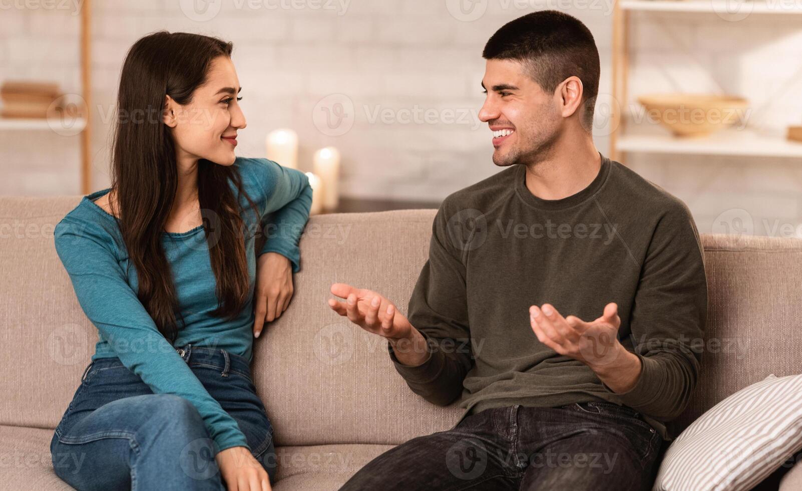 Beautiful couple talking, sitting on couch at home, have a nice conversation at their cozy apartment photo