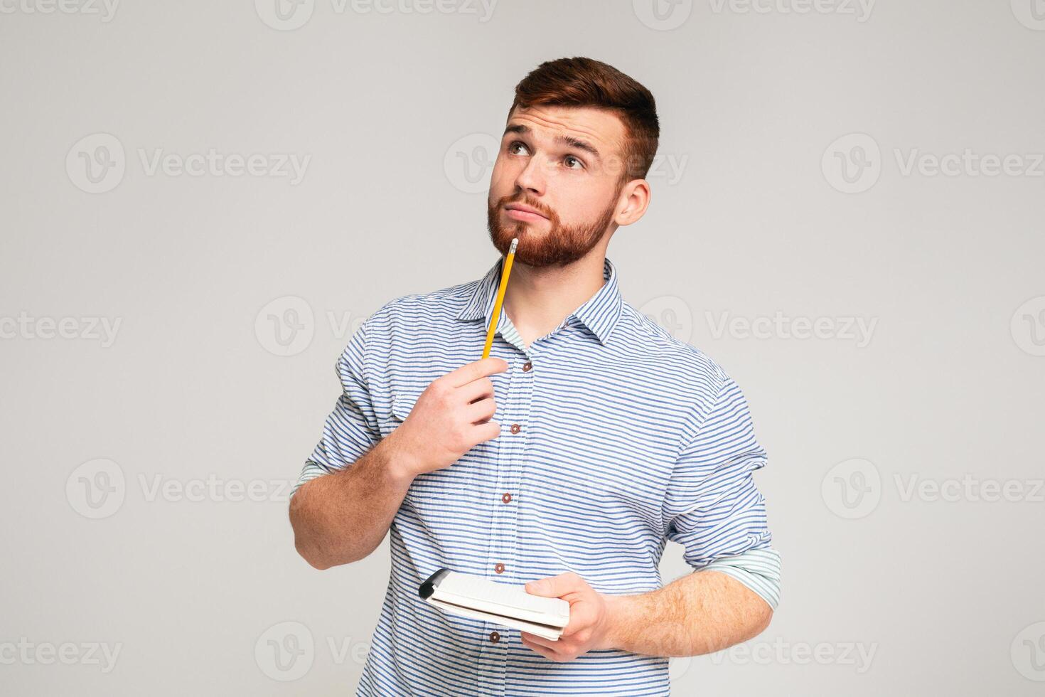 Paper note. Young man thinking about checklist what to do with pencil in hand, looking at copy space photo