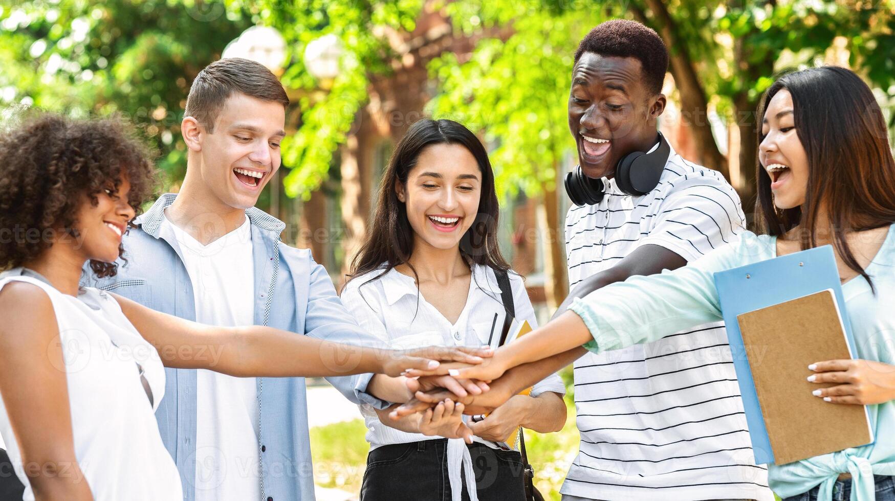 Friendship, Unity And Students Teamwork Concept. Group Of University Friends Stacking Hands Outdoors After Successful Exams Pass photo