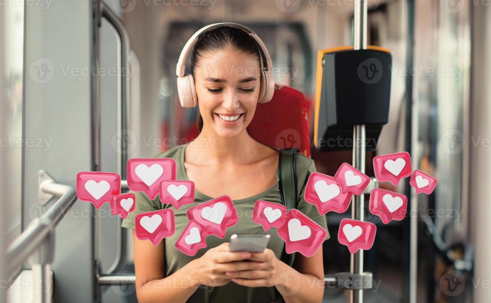 A woman sits on public transportation, using her smartphone while wearing headphones. She is smiling and appears to be enjoying her time. A number of pink heart icons are floating around her photo