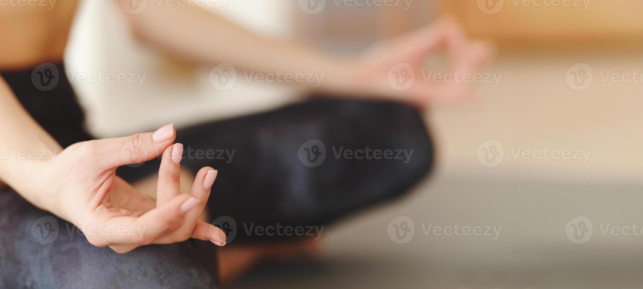 A woman sits cross-legged on a yoga mat, focusing on her meditation practice. She holds her hands in a mudra position, creating a peaceful and serene atmosphere. photo