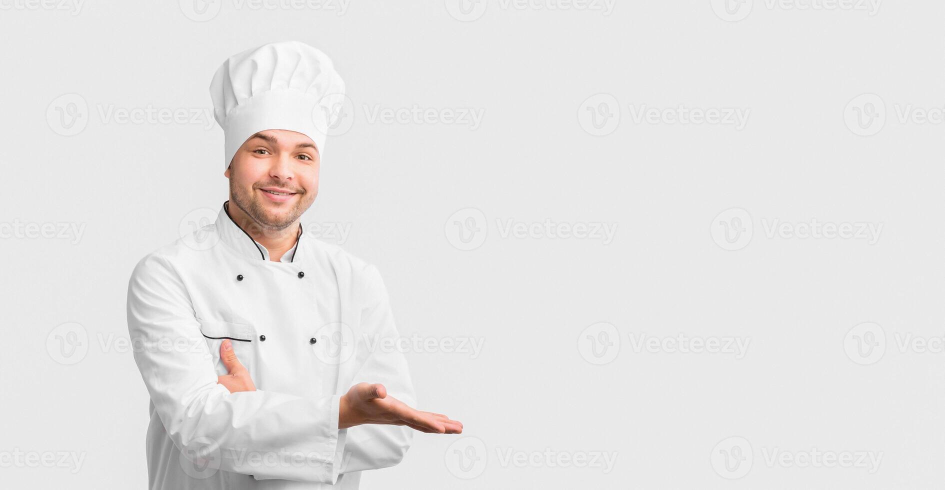 Restaurant Chef Gesturing With Hand Showing Something On Free Space Posing Over White Studio Background. photo