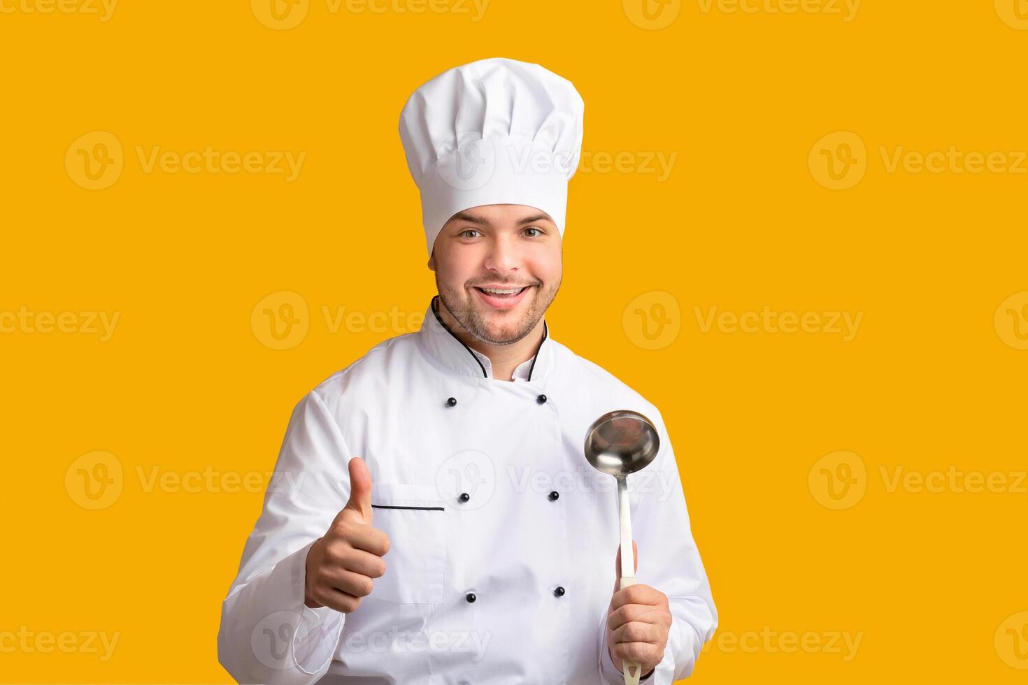 Male Chef Gesturing Thumbs Up Posing Holding Ladle Spoon Standing Over Yellow Background. Panorama, Studio Shot photo