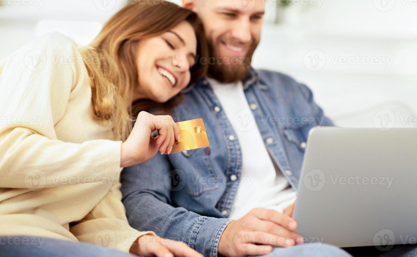 Online Shopping. Happy Couple Using Laptop And Credit Card, Resting At Home photo