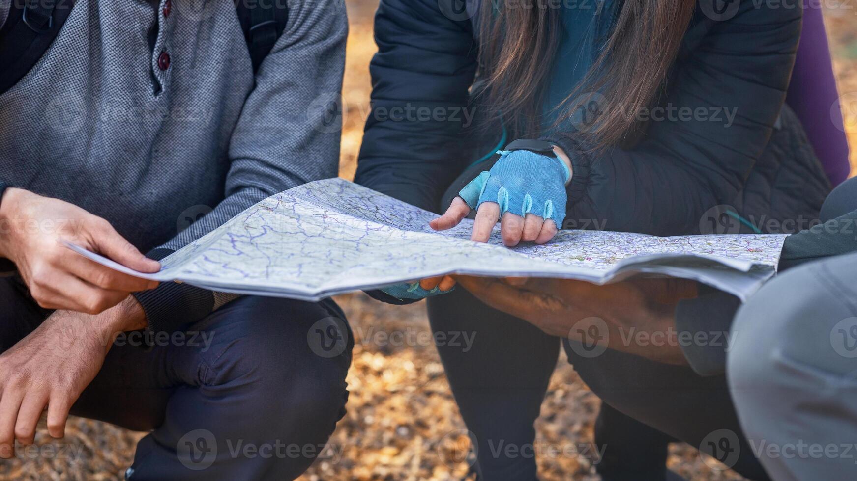 Map and navigation concept. Three unrecognizable multiethnic friends holding map, got lost at countryside, cropped photo