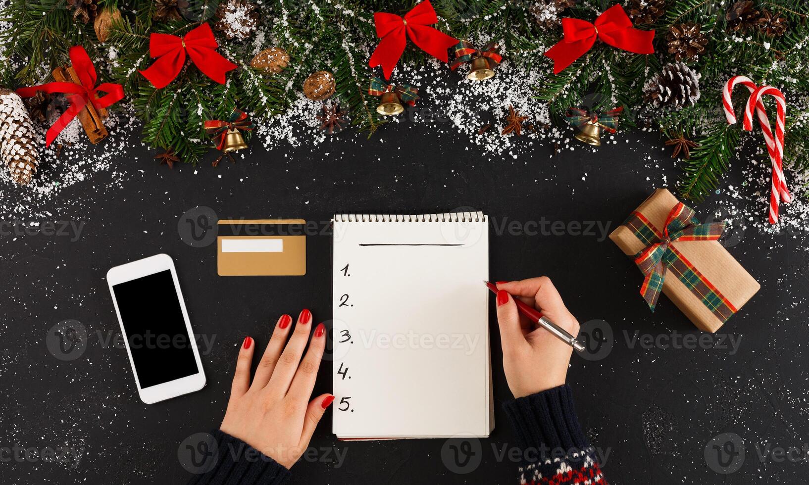 Christmas wish list writing. Woman creating present list for winter holidays. Top view, preparing for xmas and new year concept photo