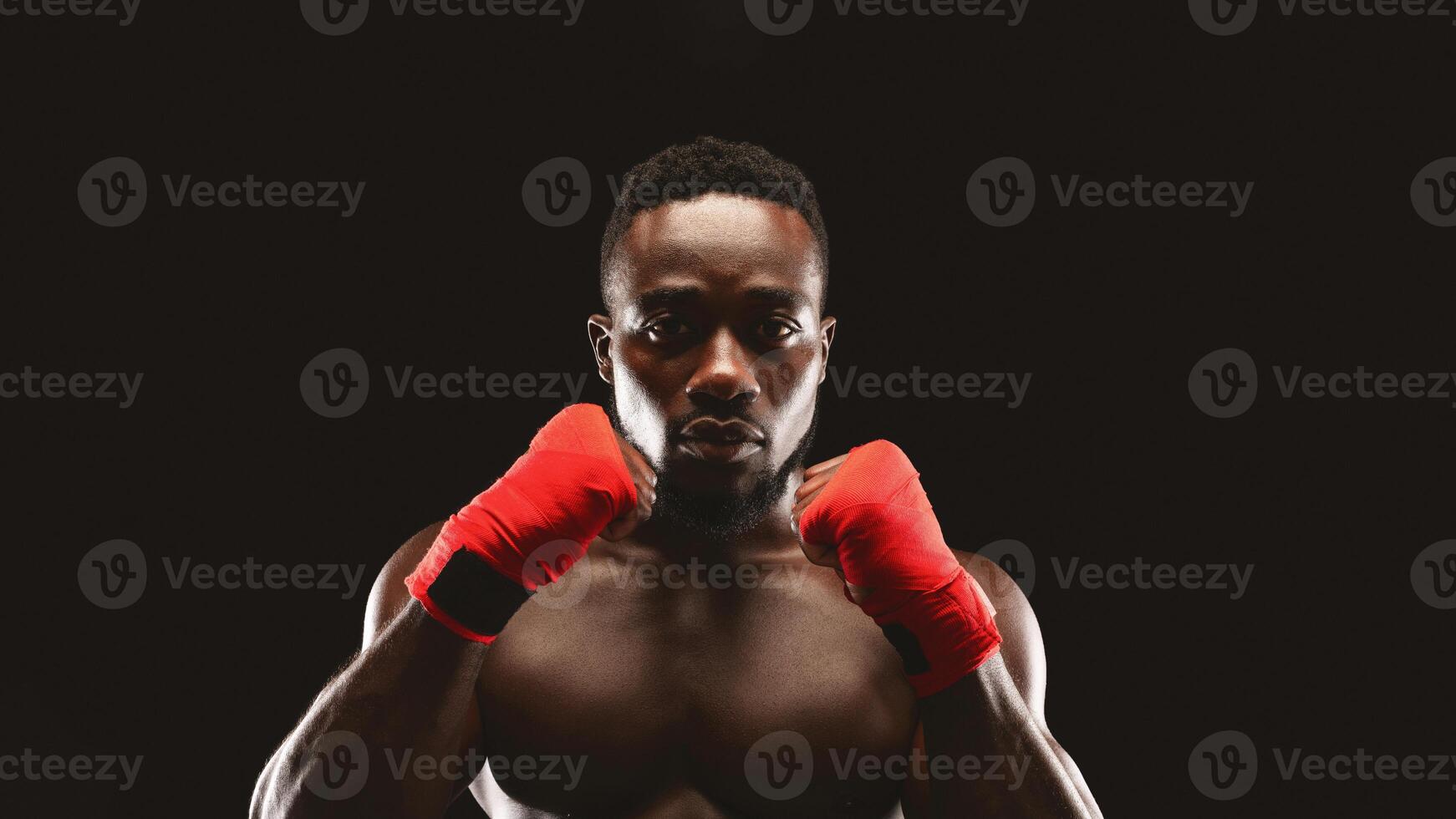 A muscular boxer stands with his hands in fighting position, ready to throw a punch. photo