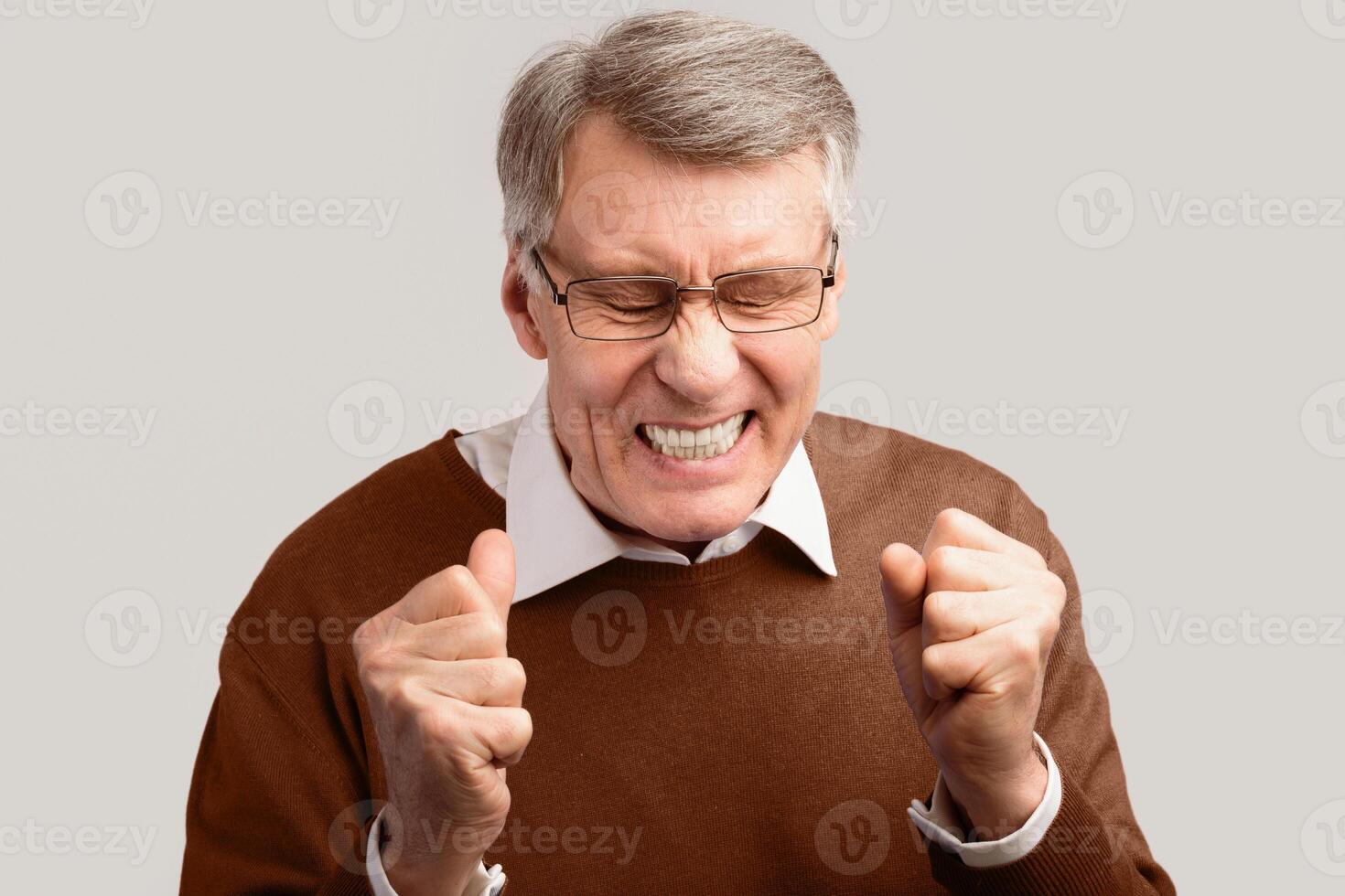 Anger. Angry Elderly Man Clenching Fists And Frowning Posing On Gray Background. Studio Shot photo