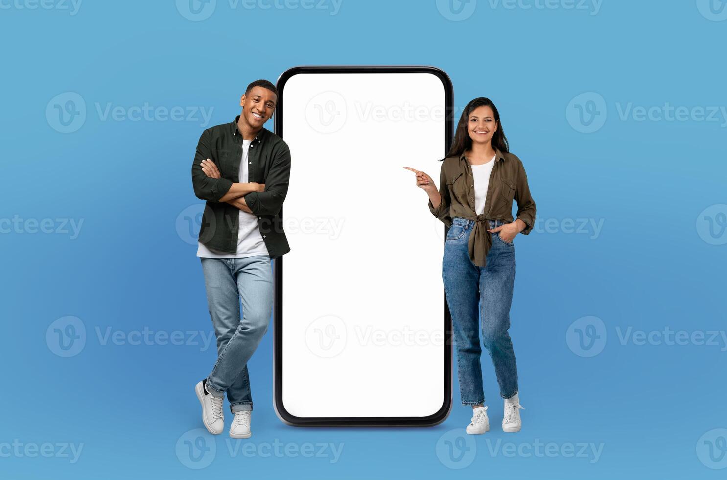 With joyful faces, the young multiethnic man and woman pose beside a blank-screened, life-sized smartphone, emphasizing the endless possibilities for customization. photo