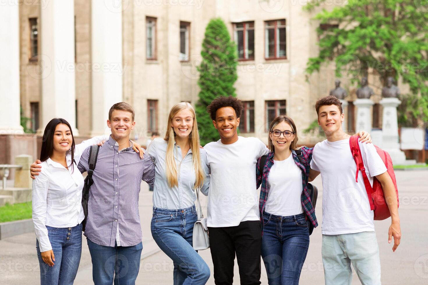 Student life. Classmates posing in front of university and smiling to camera photo