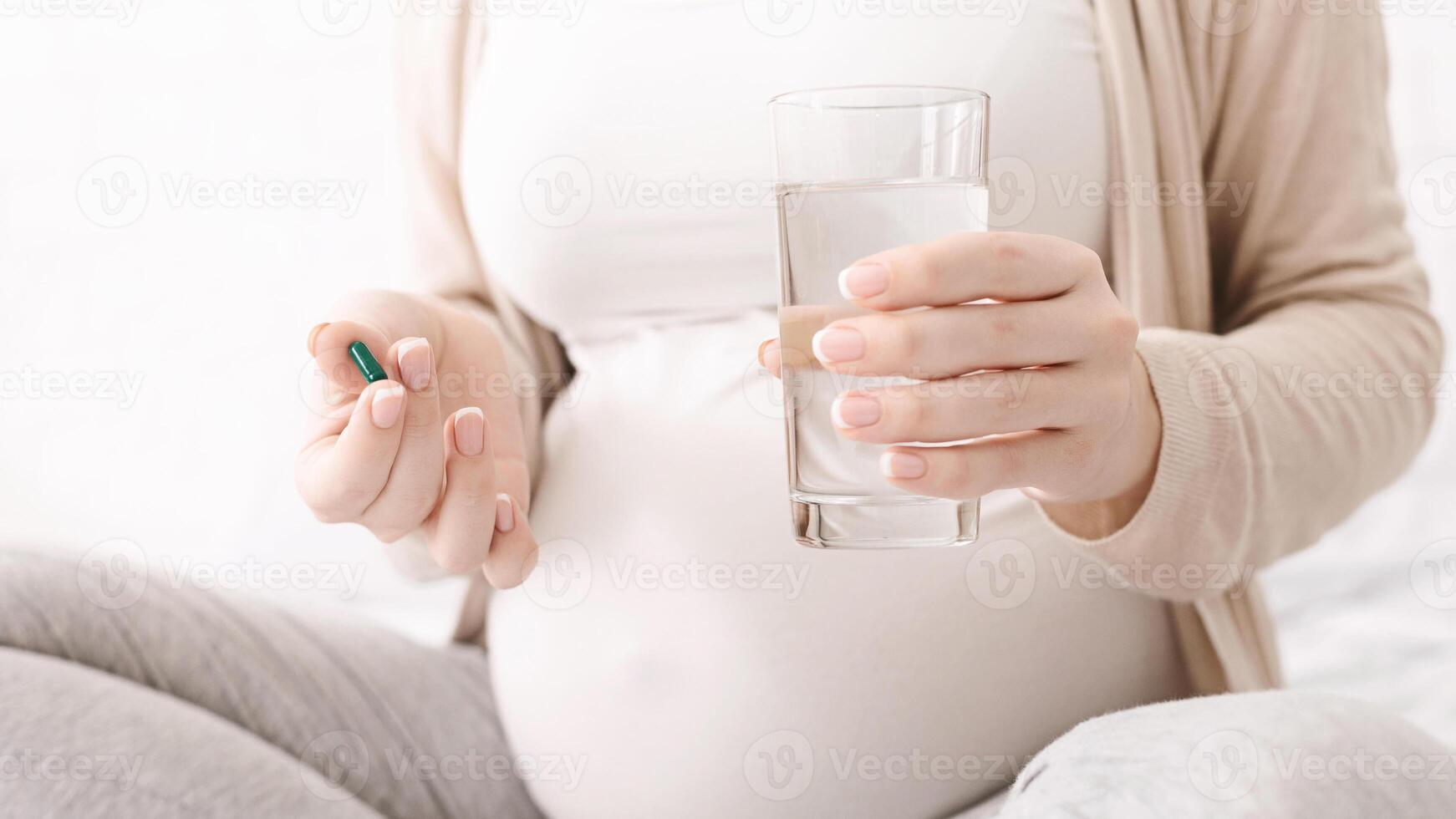 Pregnancy and medicine. Pregnant woman holding pill and glass of water, closeup photo