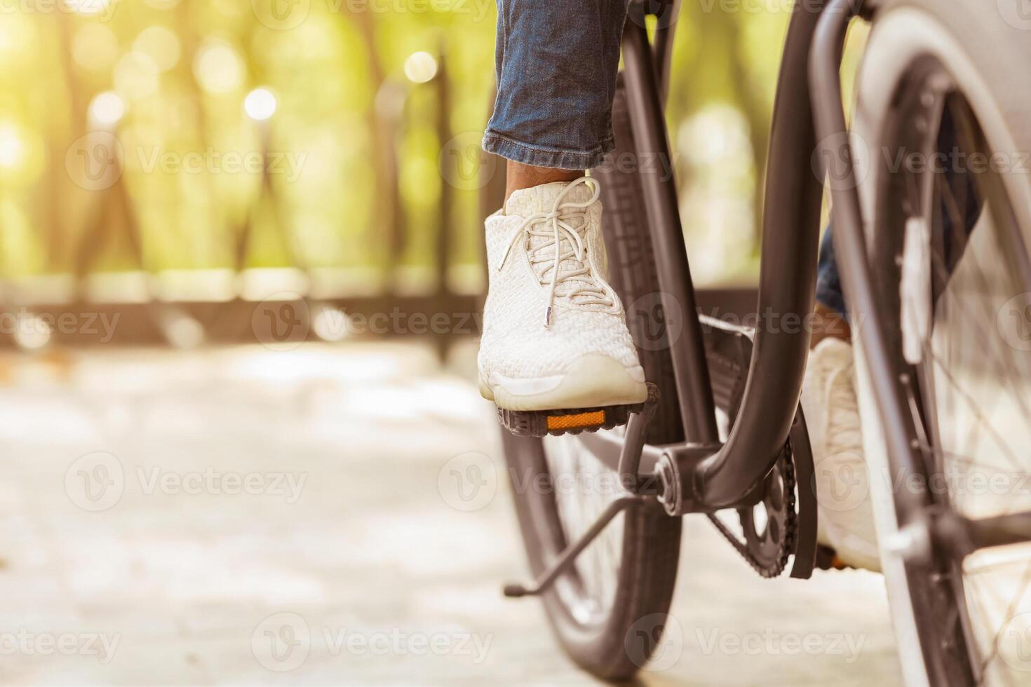 Feet On Pedals Of Unrecognizable Black Man Riding Bicycle In Park, Cropped Image, Closeup photo