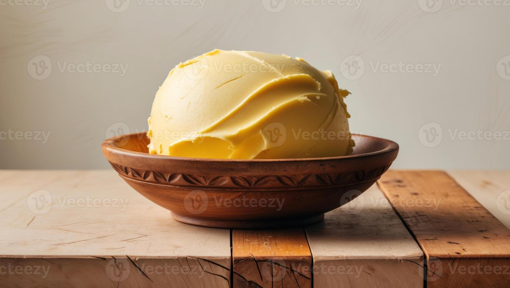 A bowl of butter sitting on a wooden table photo