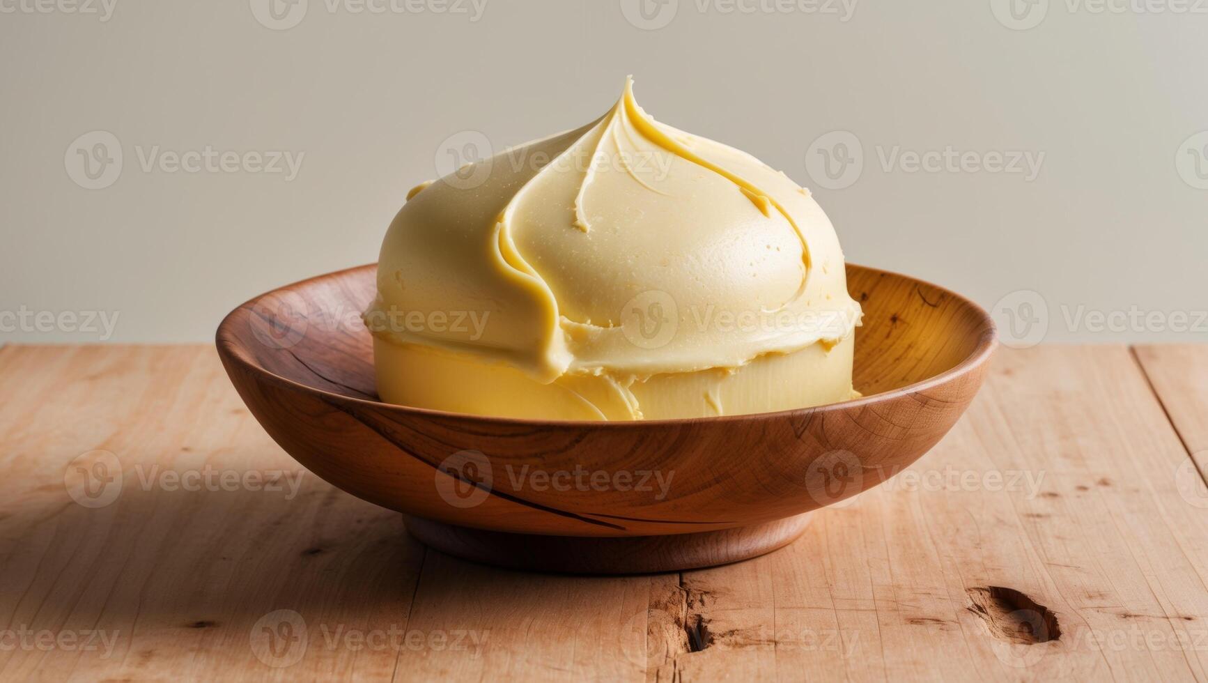 A bowl of yellow frosting sitting on a wooden table photo
