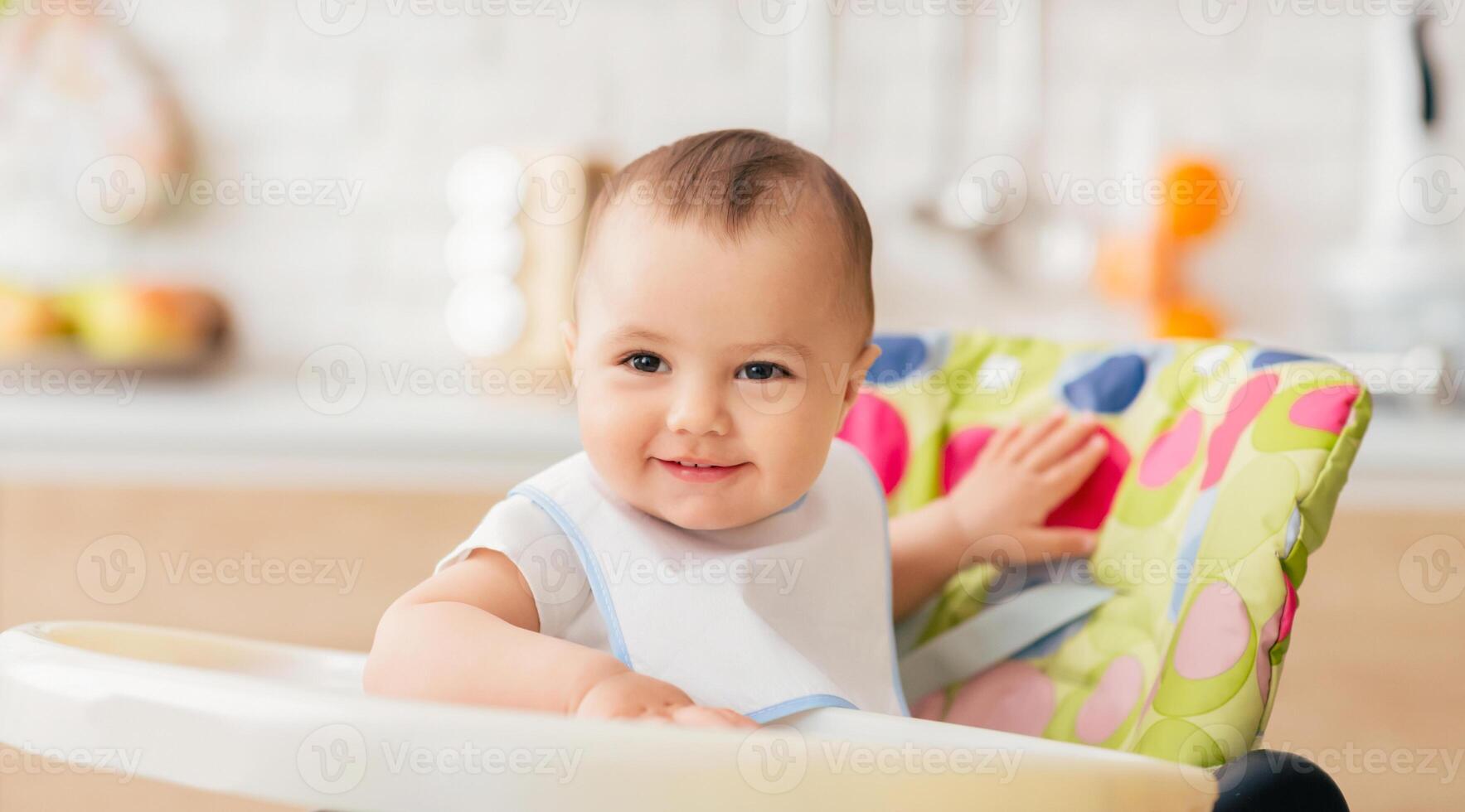 An infant is sitting in a high chair in a homey kitchen. The atmosphere is cheerful and relaxed, highlighting the simple joys of mealtime in a family kitchen. photo