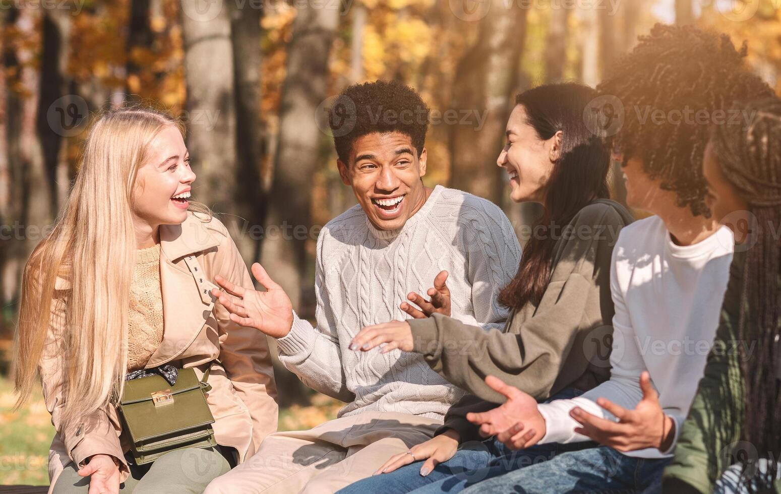 Group of happy international teenagers talking and laughing in park, close up photo