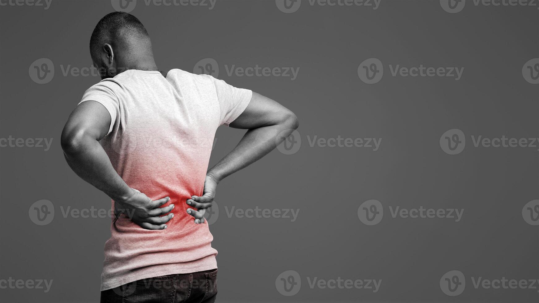 Afro guy holding both hands on lower back, pain in spine, inflamed zone highlighted in red, white background, free space photo