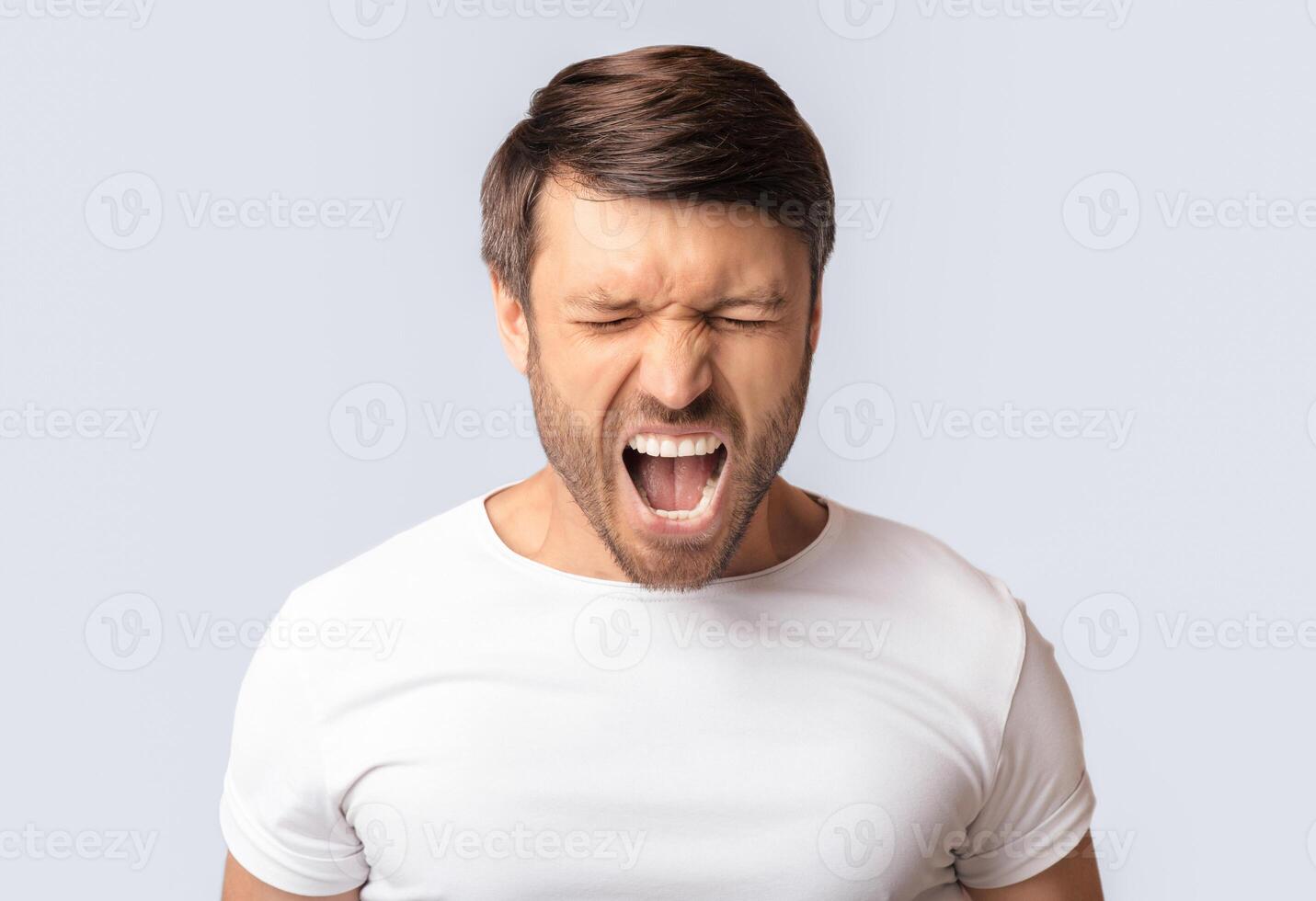 Anger Expression. Portrait Of Crazy Man Shouting Furiously Over White Studio Background. Copy Space photo