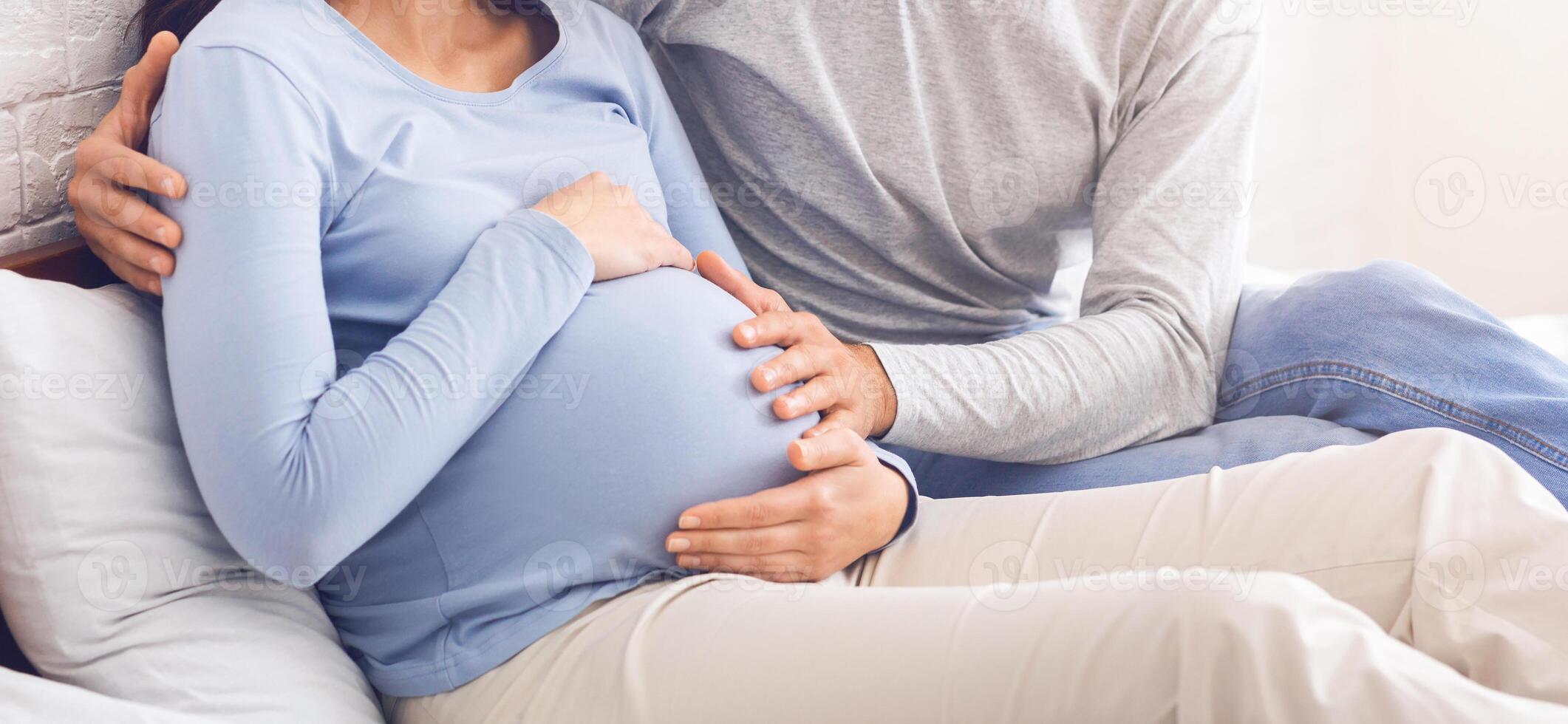 Worried husband embracing his pregnant wife that feeling unwell while sitting on bed at home, free space photo