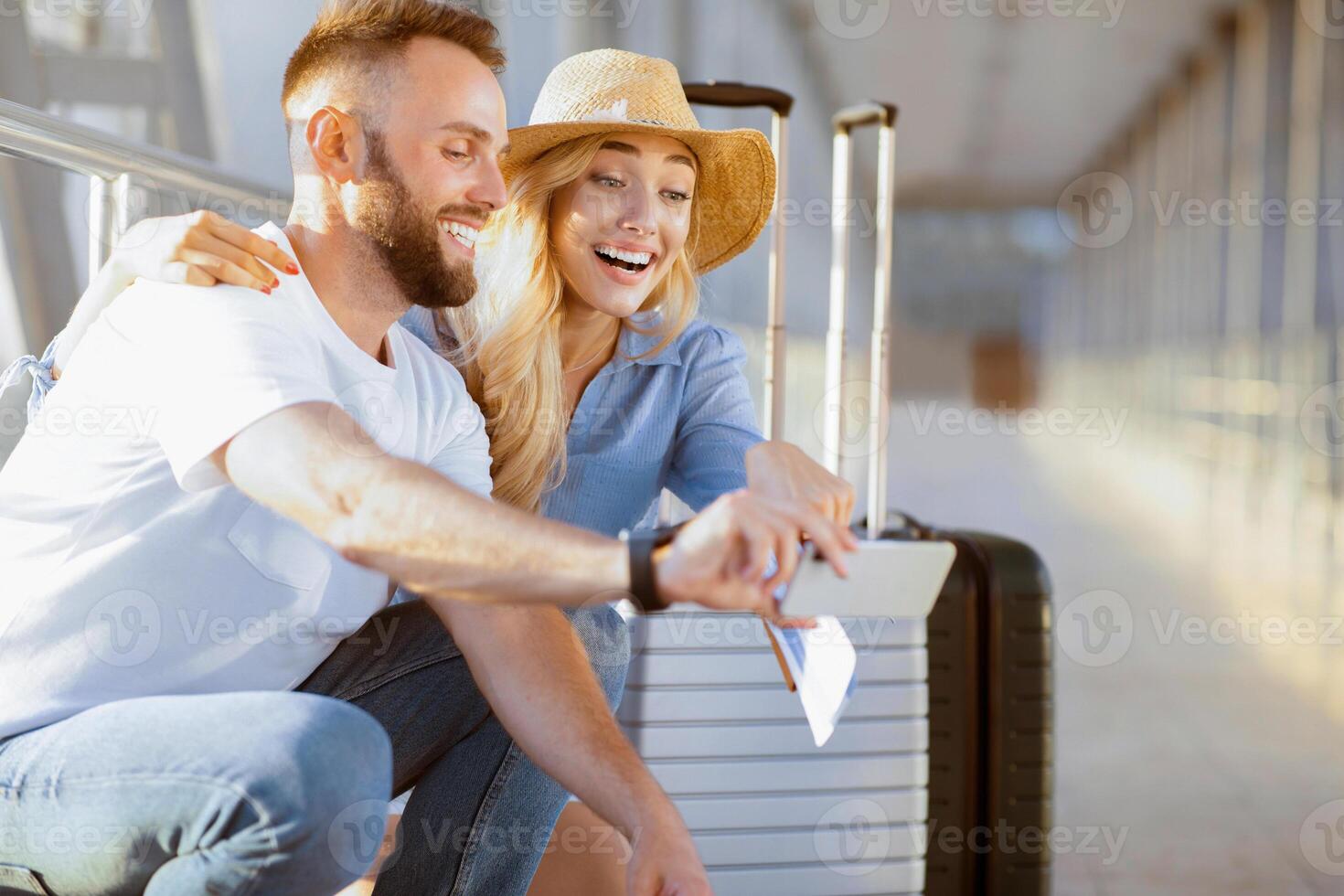 Excited couple in airport using smartphone, searching sightseeings, waiting for departure, free space photo