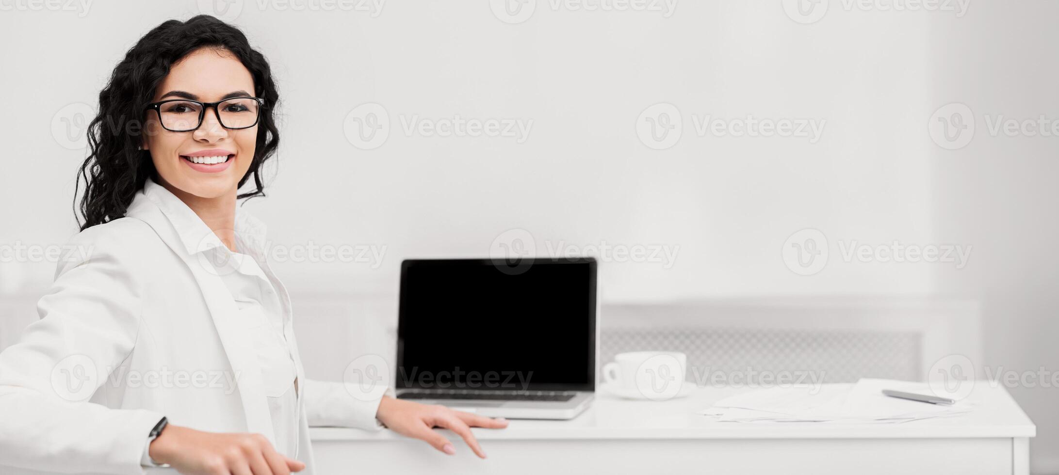 Online Course, Workshop. Happy mexican woman smiling at camera near computer with blank screen, mock up, copyspace photo