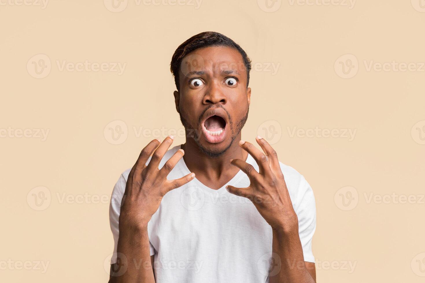 Fear. Frightened Black Man Screaming Looking At Camera Holding Hands Near Face Standing Over Yellow Background In Studio photo