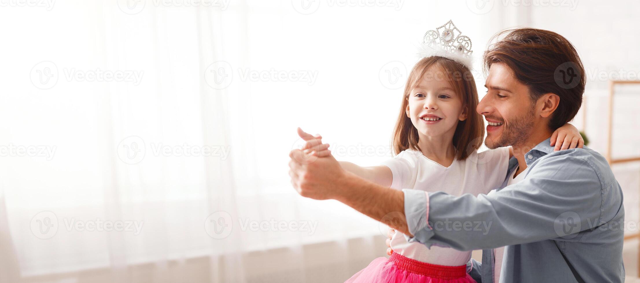 Close up of handsome cheerful dad dancing with his princess little daughter indoor, happy to be father, copy space photo