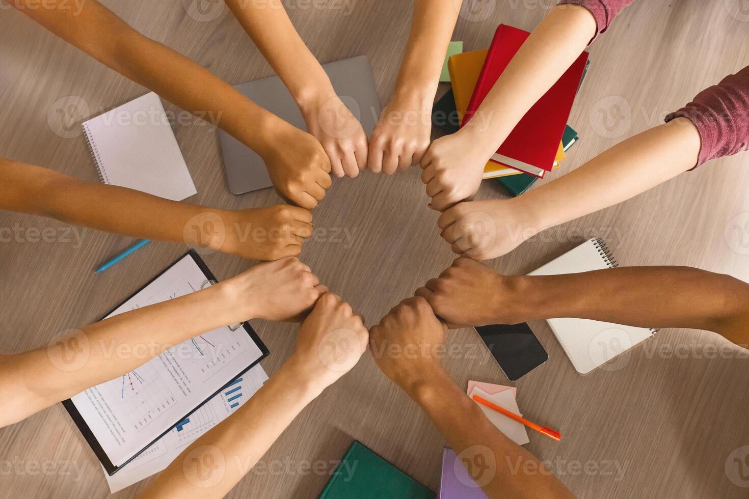 Multiracial students joining hands together, preparing common academic project, top view photo