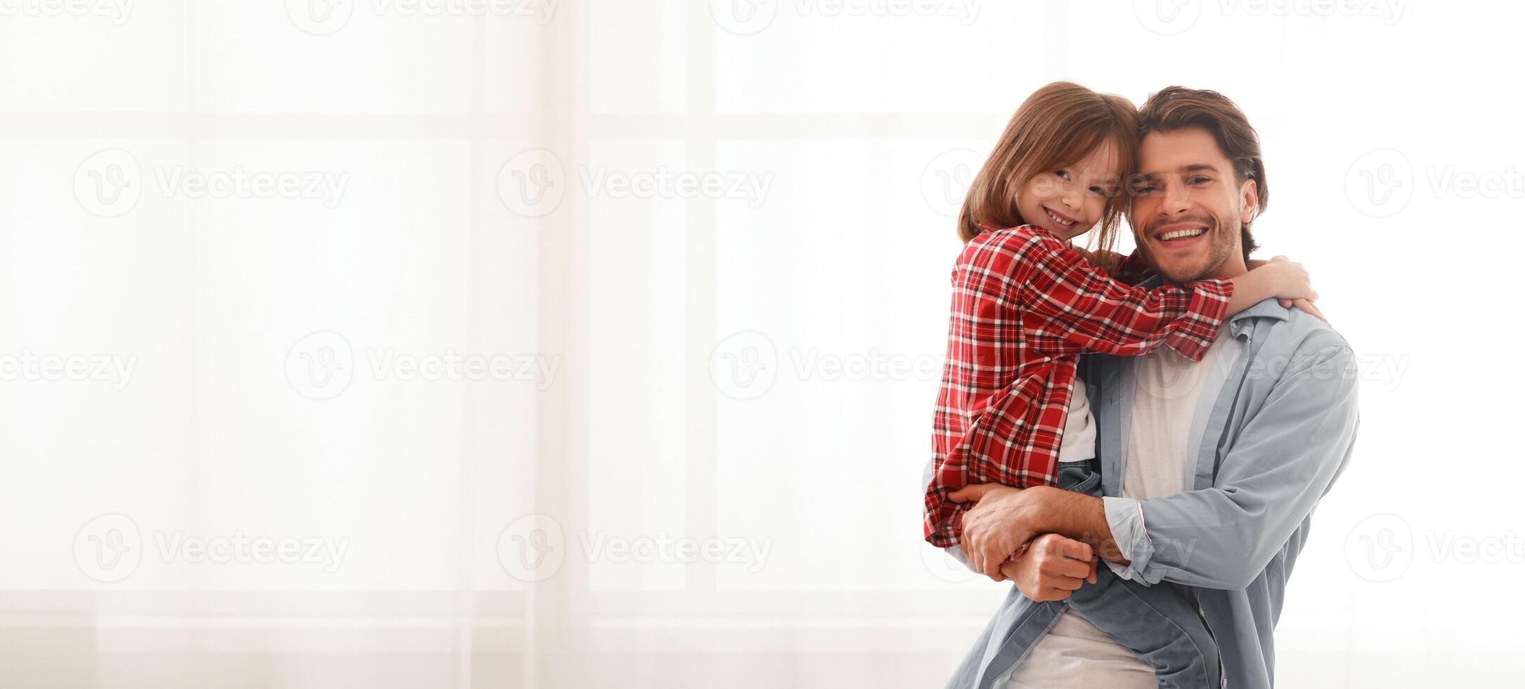 Smiling daddy and daughter posing at home over big window, copy space photo
