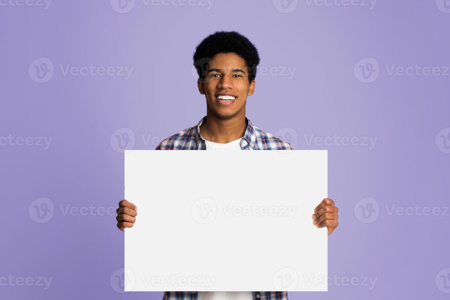 Happy guy showing blank placard with copy space for your text, pink background photo