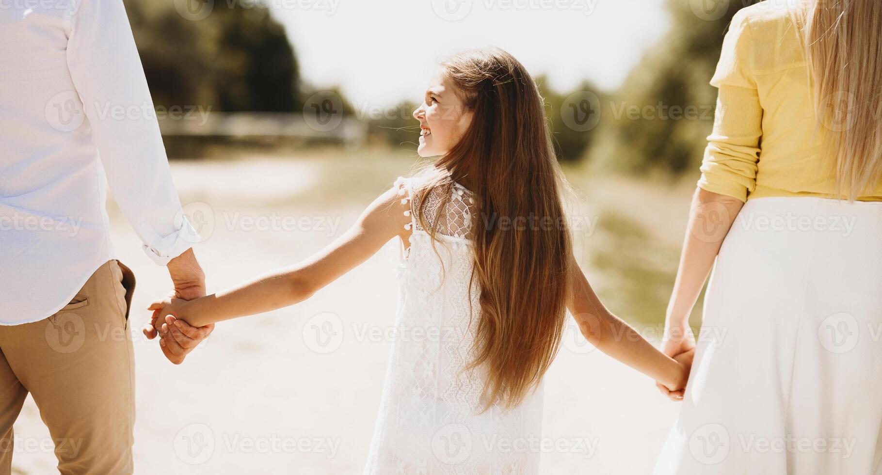 Family walk. Parents and little girl enjoying walk in countryside, holding hands photo