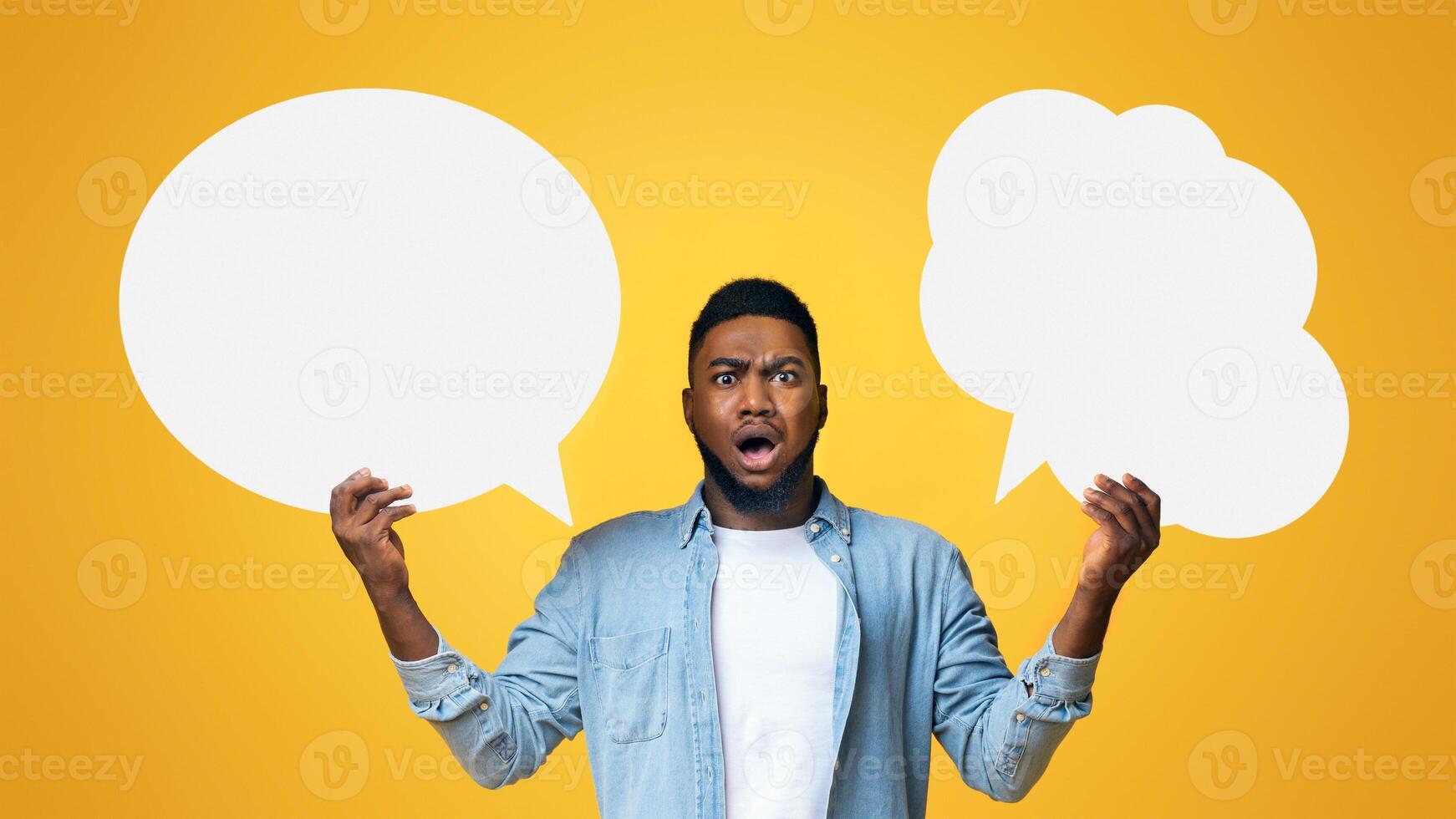 Complex choice. Confused black guy holding two speech bubbles on yellow background, panorama photo