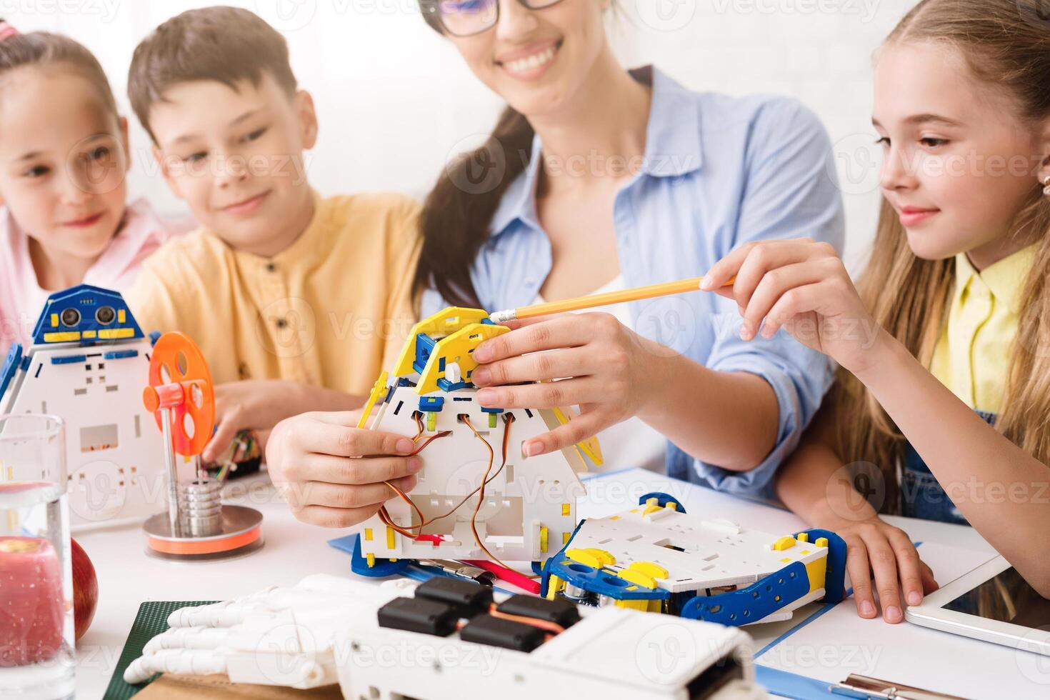 A teacher guides a group of children as they work together to build a robot. The students are focused and engaged, learning about STEM concepts through hands-on experience. photo