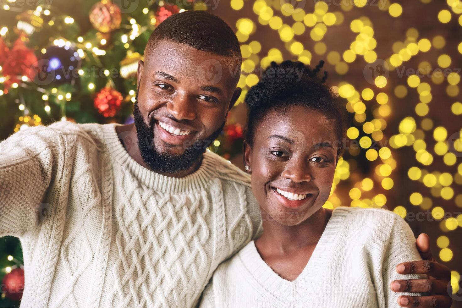 Xmas selfie. Happy black couple taking self-portrait with Christmas tree on background, celebrating holidays. photo