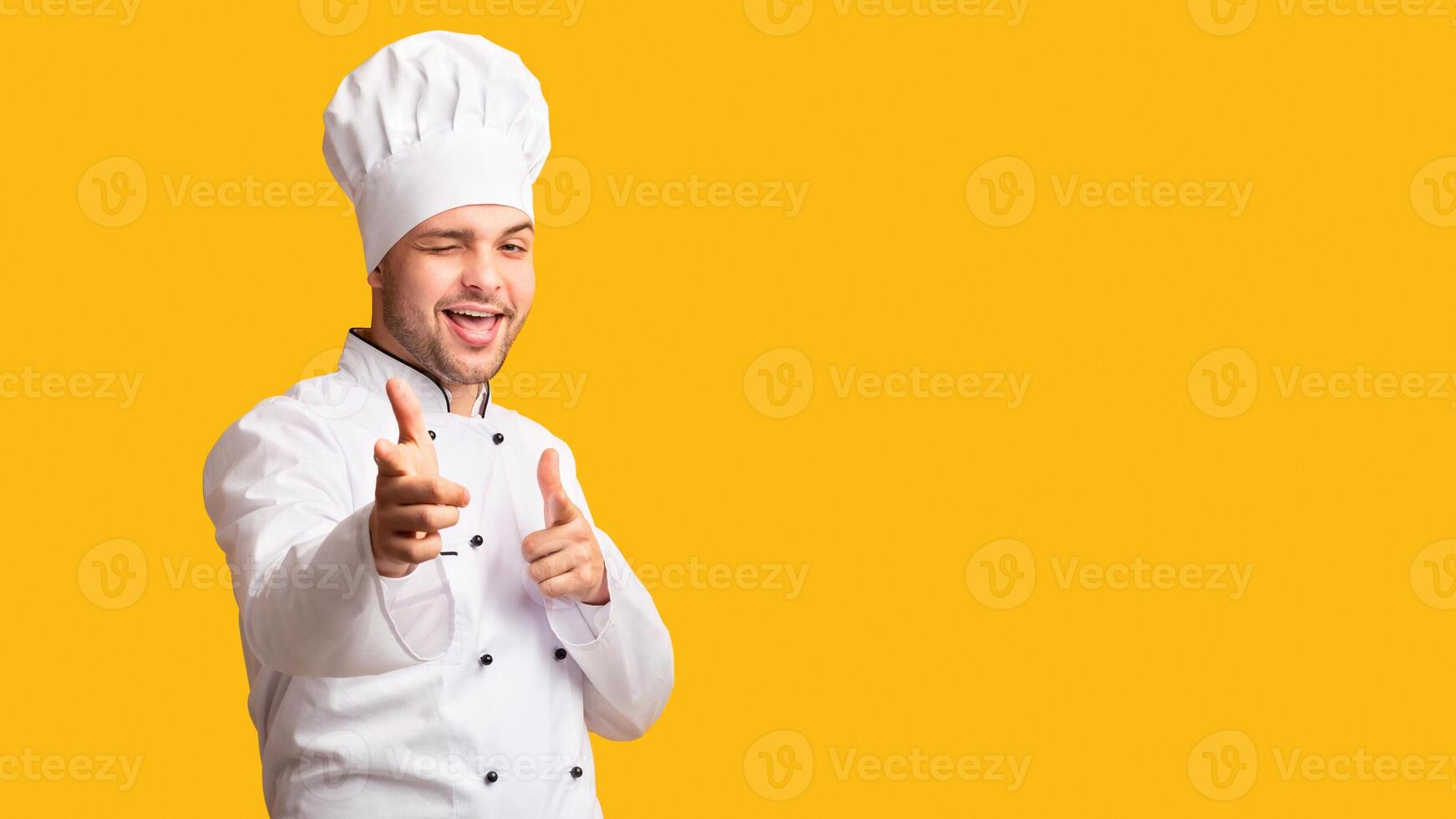 I Choose You. Cheerful Chef Man Pointing Fingers Winking At Camera Standing On Yellow Background. Studio Shot, Panorama photo