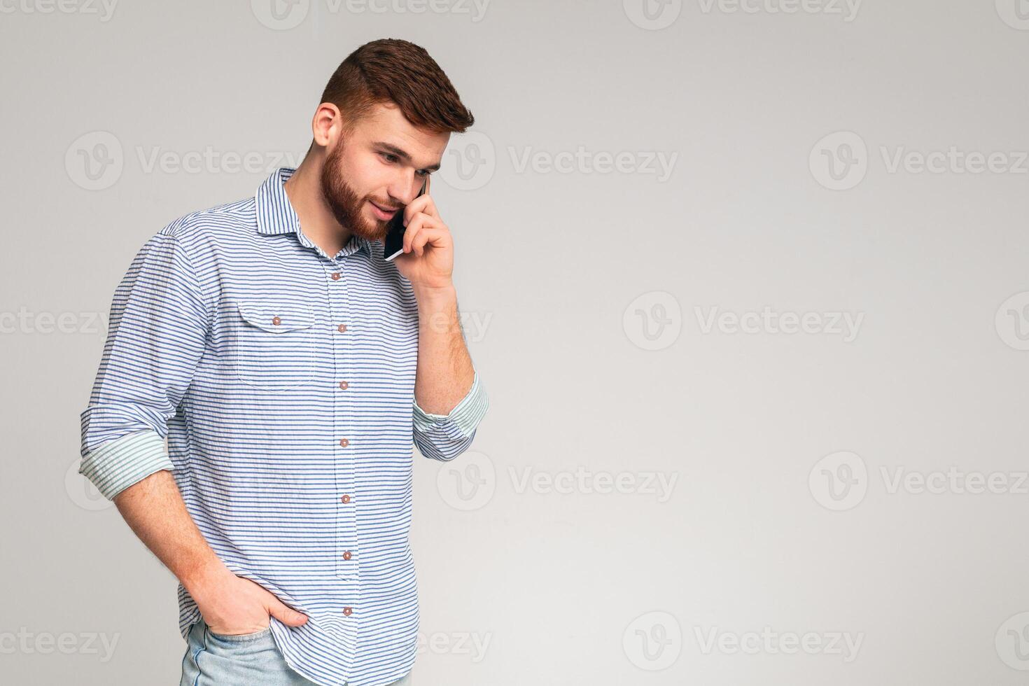 Handsome man talking on cellphone and looking away on studio background, panorama, copy space photo
