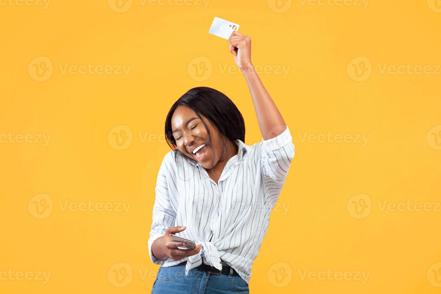 Happy Black Girl Dancing Holding Phone And Credit Card Having Fun Over Pink Background. Studio Shot photo