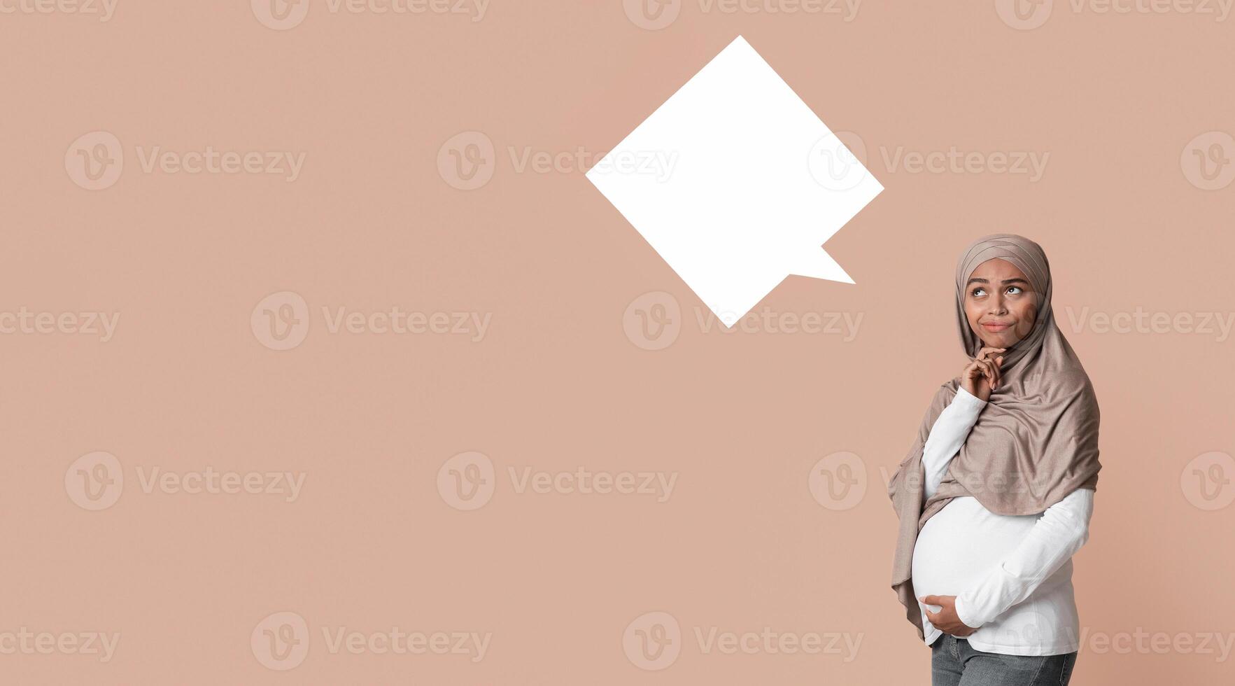 Boy Or Girl. Thoughtful black pregnant muslim woman in hijab posing between two speech bubbles over yellow background, free space photo