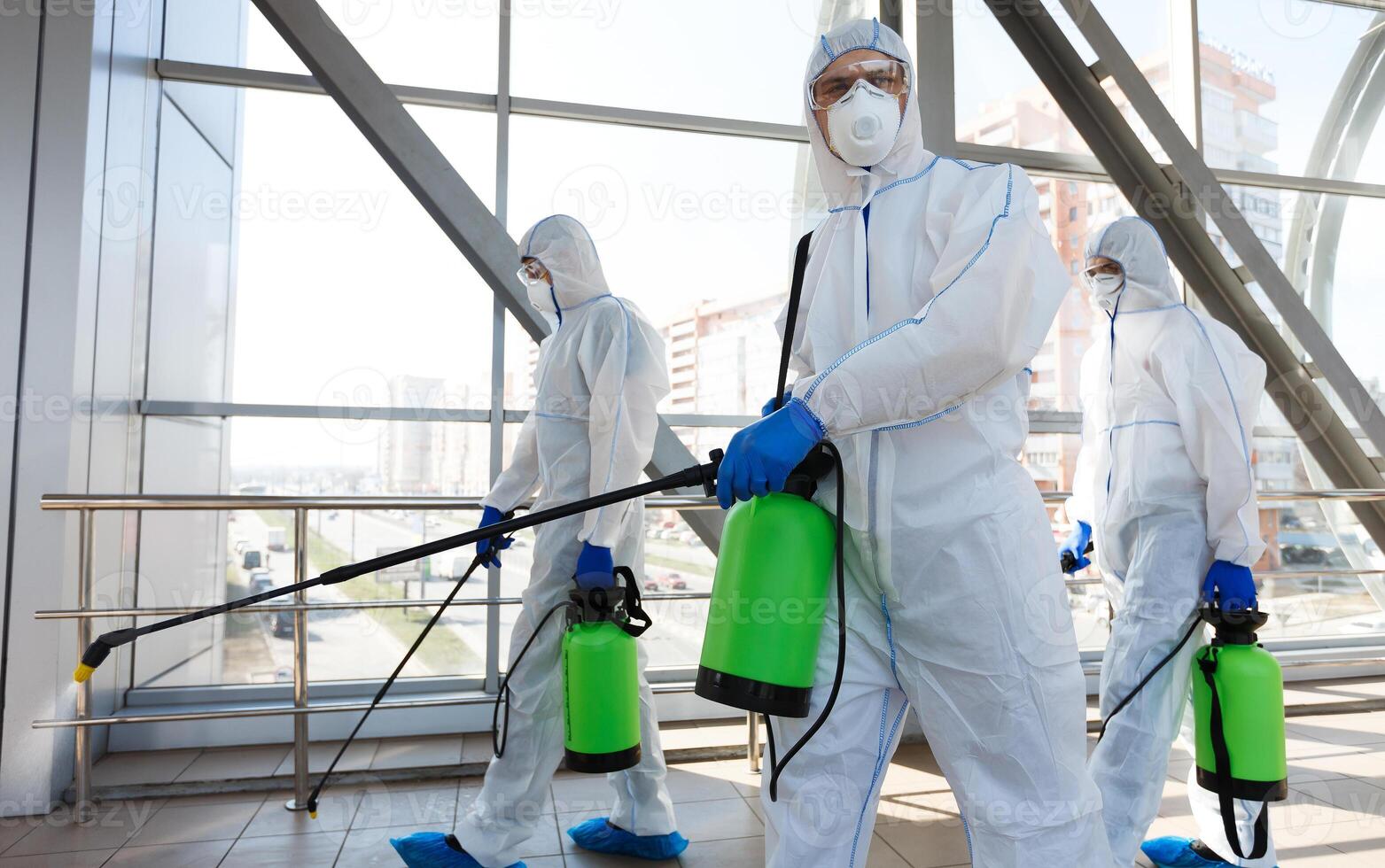 Professional workers in hazmat suits disinfecting indoor accommodation, pandemic health risk, coronavirus photo