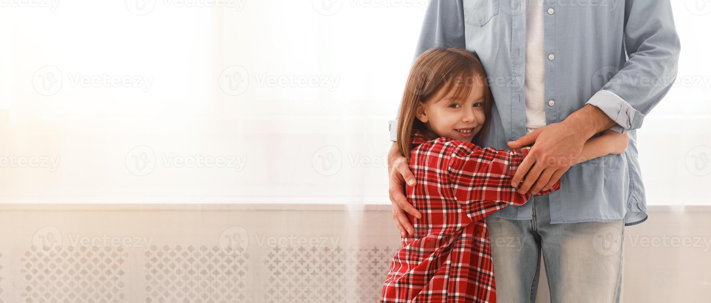 You are my hero. Sweet smiling little girl hugging her dad at home, staying next to window, close up, copy space photo